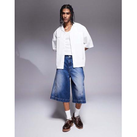 ASOS DESIGN - Denim jorts met langere pijpen en slijtageplekken in blauw met mid-wash
