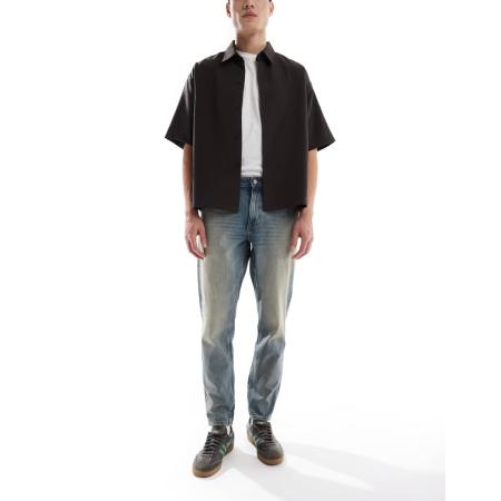 ASOS DESIGN - Toelopende jeans met tint in lichtblauwe wassing